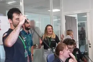 Spontaneous moment of joy among HyPrSpace engineers during a successful test, showing team members smiling and cheering in a brightly lit control room.