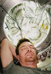 HyPrSpace team member resting inside a metallic test chamber surrounded by wires and instrumentation, illustrating the human dedication behind cutting-edge space technology.
